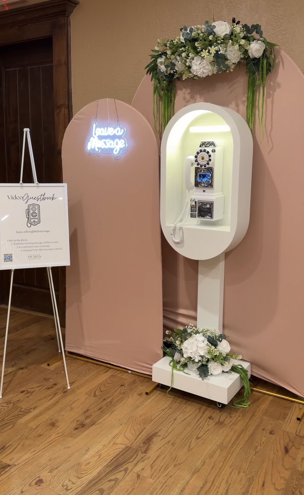 The white phone booth with its arches, white florals, neon sign and instruction sign